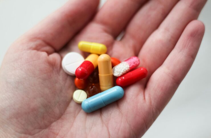 A person holding a variety of pills in the palm of their hand.