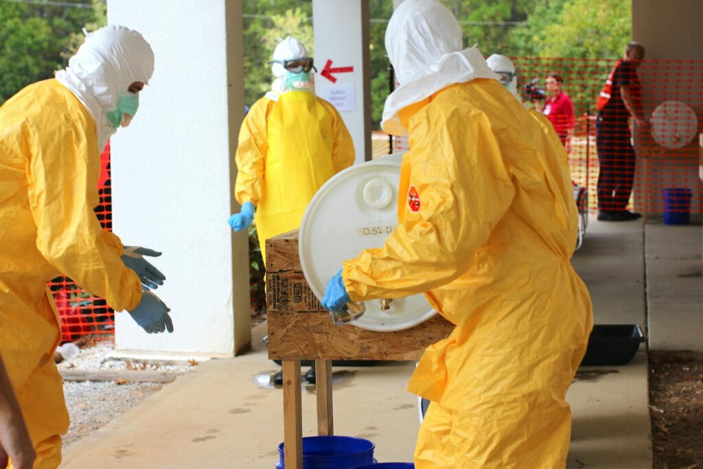 Professionals in yellow PPE suits attending to a procedure outdoors for safety training.