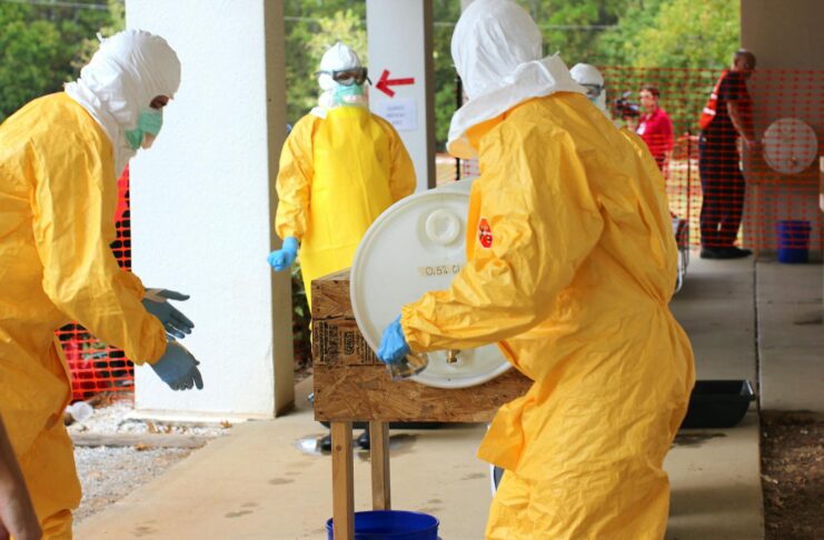 Professionals in yellow PPE suits attending to a procedure outdoors for safety training.