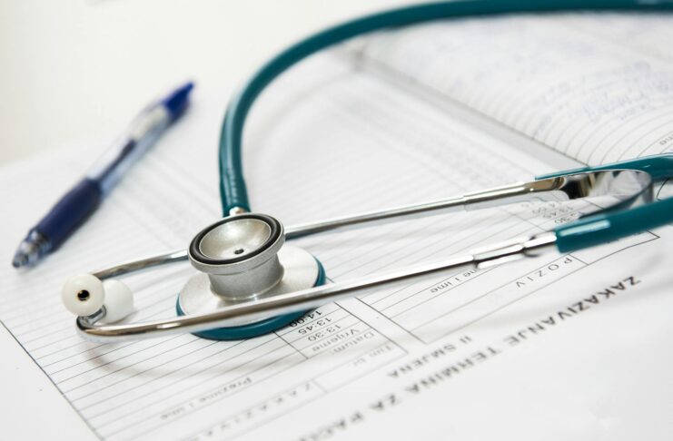 A stethoscope and pen on a medical report in a healthcare setting.