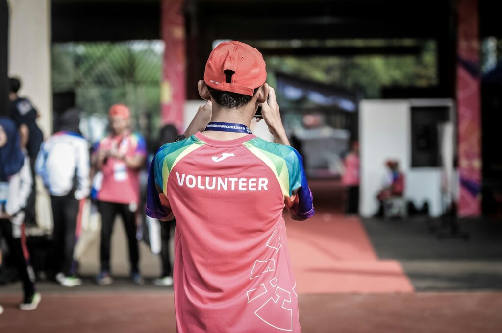 A person standing wearing red shirt with Volunteer written on it.