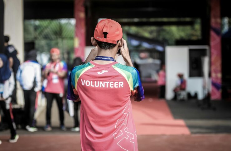 A person standing wearing red shirt with Volunteer written on it.