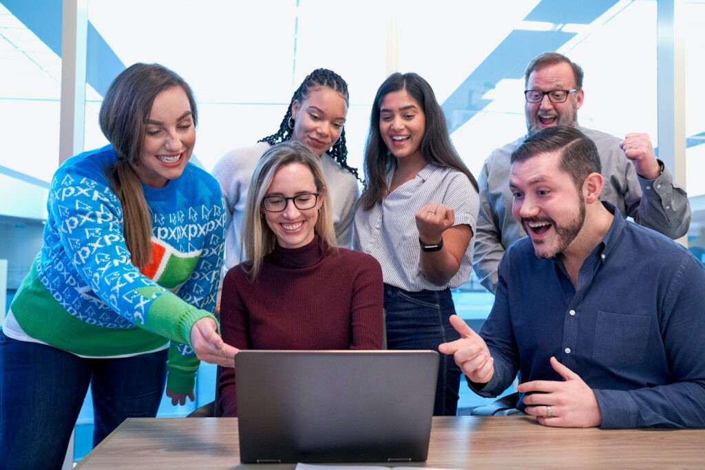 A group of smiling staff gathered around a laptop.