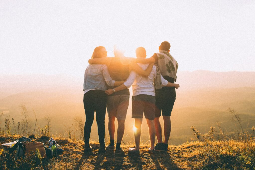 A group of people outside and in front of a sunset.