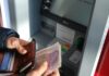 UK Employees ‘Absorb the Hidden Costs of Modern Work’ A person holding brown leather wallet and banknotes at an ATM.