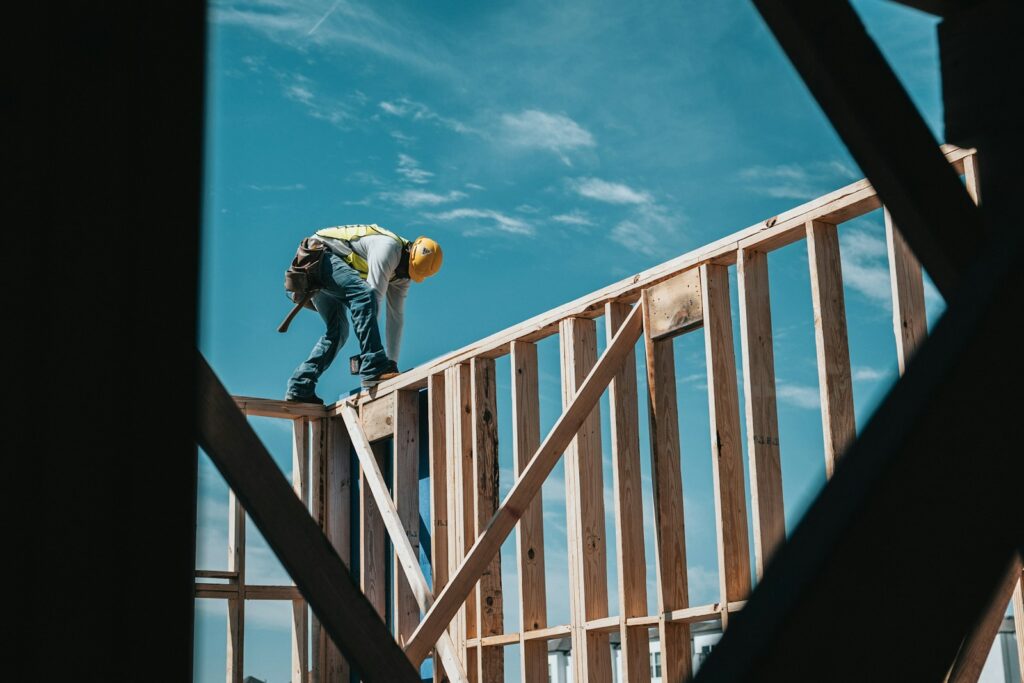 A construction worker walks along a timber structure.