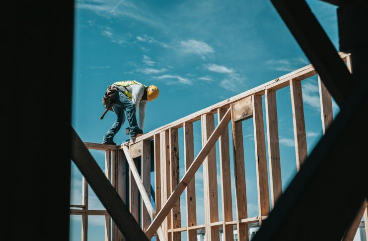 A construction worker walks along a timber structure.
