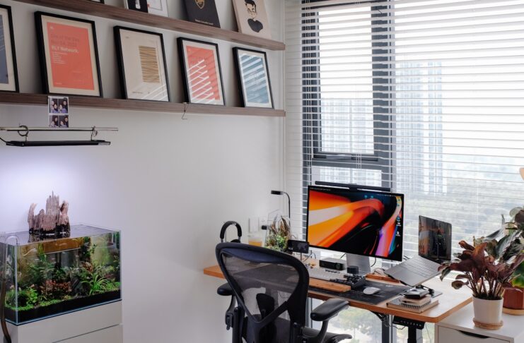 A modern home office with framed art and an aquarium.