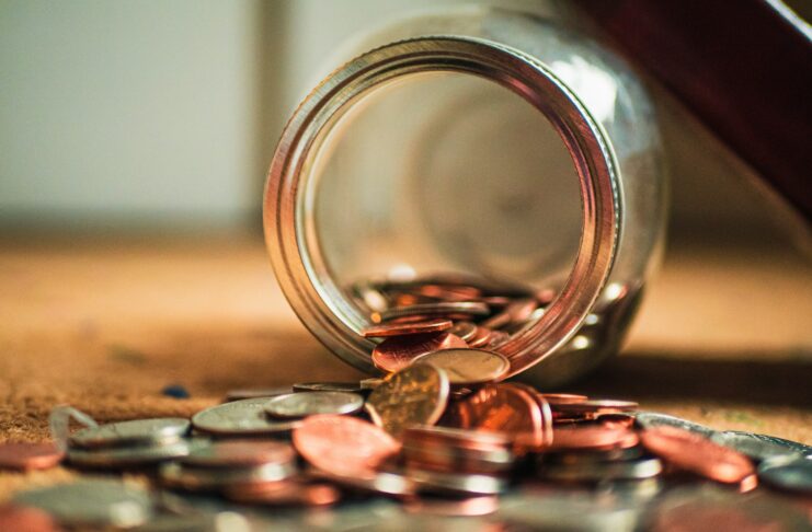 Coins spilling out of an overturned jar.
