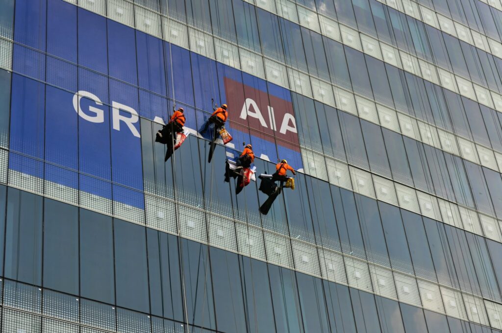 Workers placing a sign on a high-rise building.