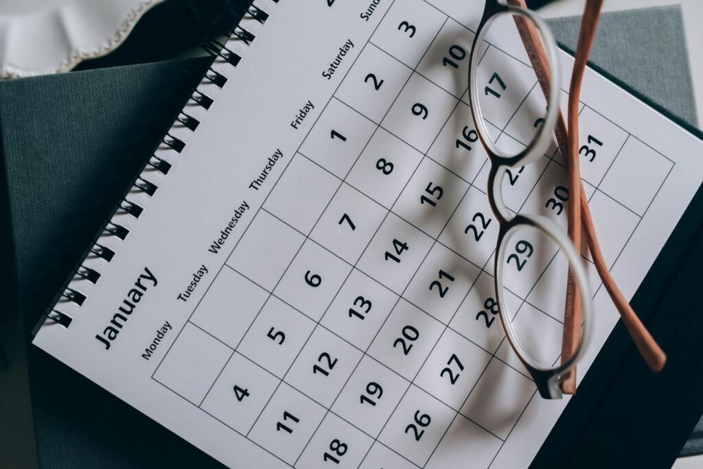A close-up of a January calendar with eyeglasses on a table, emphasising planning and organization.
