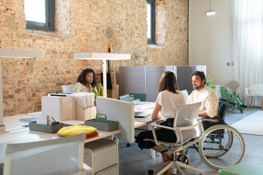 Staff at an office desk, including a man in a wheelchair.