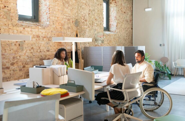 Staff at an office desk, including a man in a wheelchair.