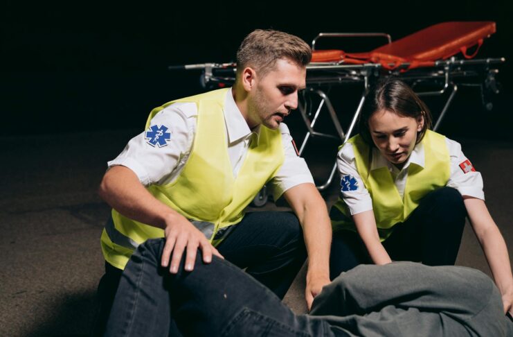 Paramedics provide emergency assistance to an injured person outdoors at night.