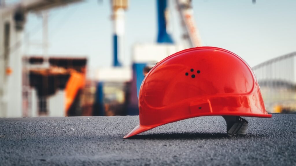 A red construction safety helmet lies on the ground.