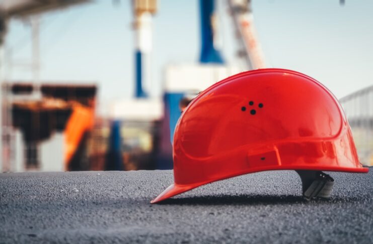 A red construction safety helmet lies on the ground.