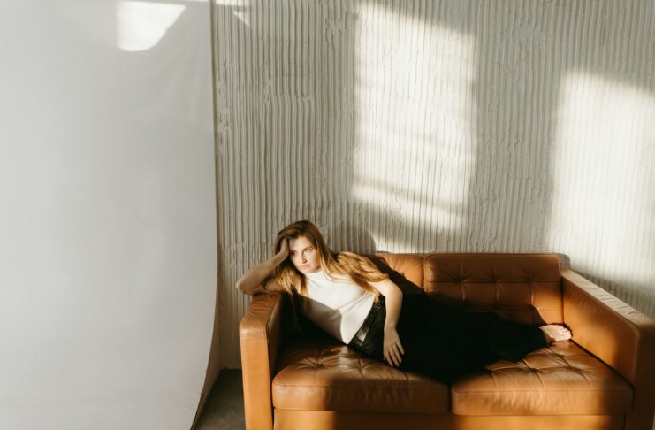 A woman relaxes on a brown couch.