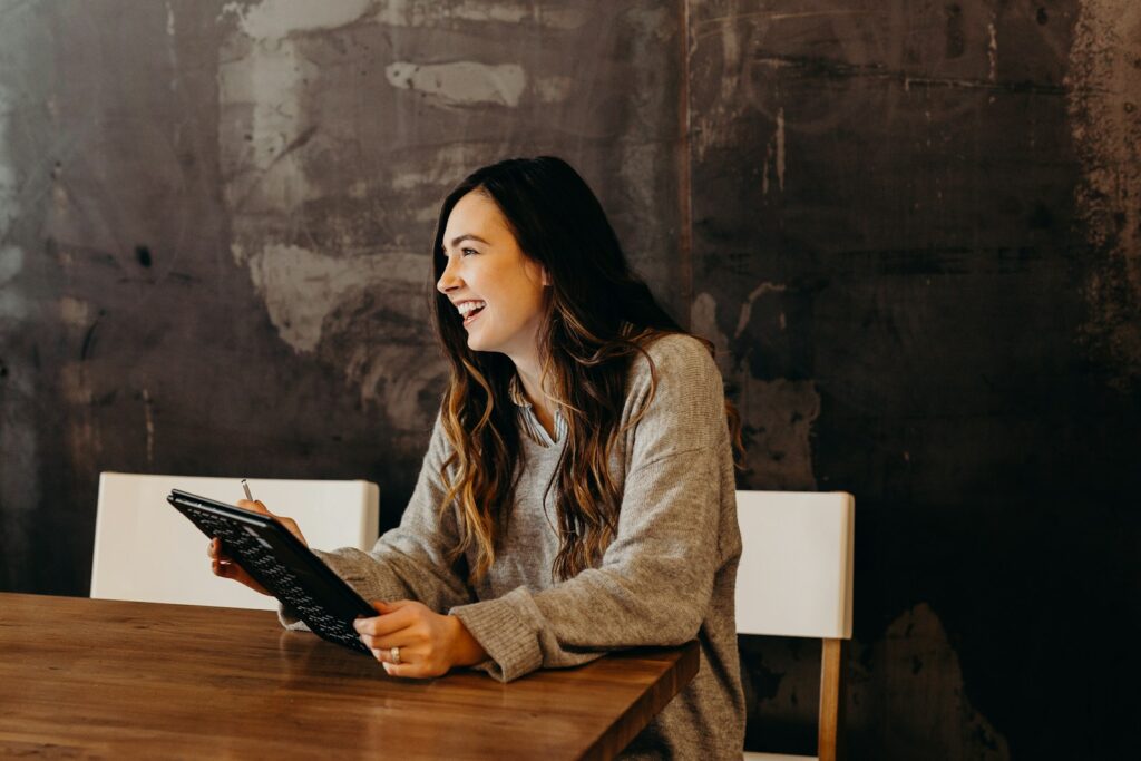 A woman laughs while sitting at a table with a folder.