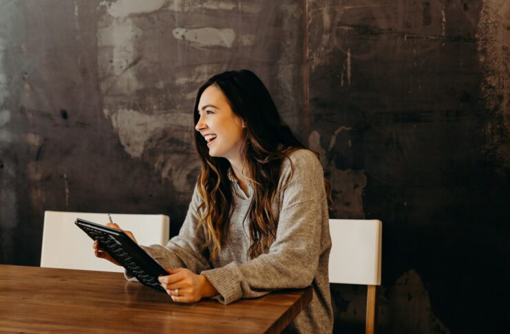 A woman laughs while sitting at a table with a folder.