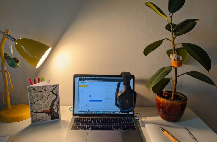 A home office with computer, light and a plant.