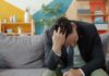 Men Still Lag Behind Women in Accessing Mental Health Support: Report Man in suit sitting on couch with head in hands.