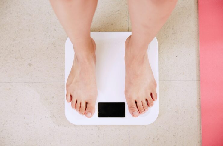 A person weighing themselves on a bathroom scales.