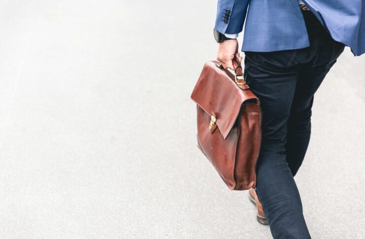 person walking holding brown leather bag