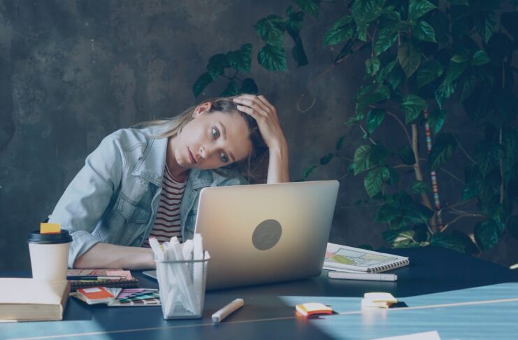 A woman appears stressed while working on a laptop.