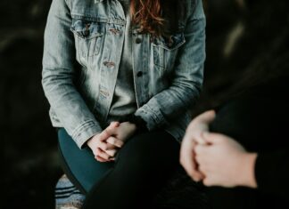 Most Workers Still Fear Speaking About Mental Health, Study Finds The lower half of two people sitting with their hands folded.