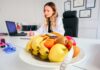 Calls Grow for Wellbeing Incentives as Budget Offers Little Relief for Overstretched Employers A woman sitting at a desk with a bowl of fruit by her side.