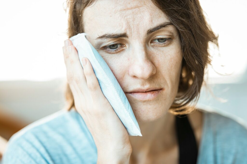 A woman holding a cool cloth to her face.