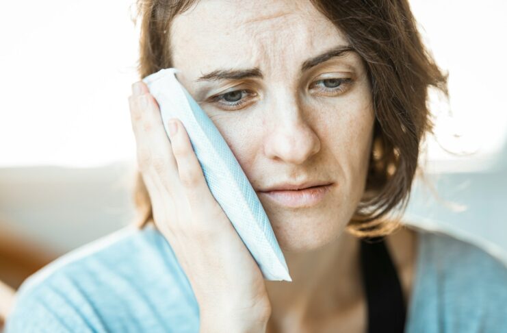 A woman holding a cool cloth to her face.