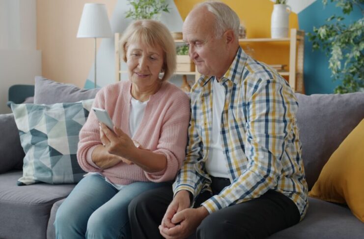 Elderly couple looking at a smartphone together on couch.