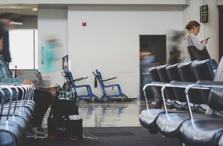 man sitting on chair watching woman holding phone