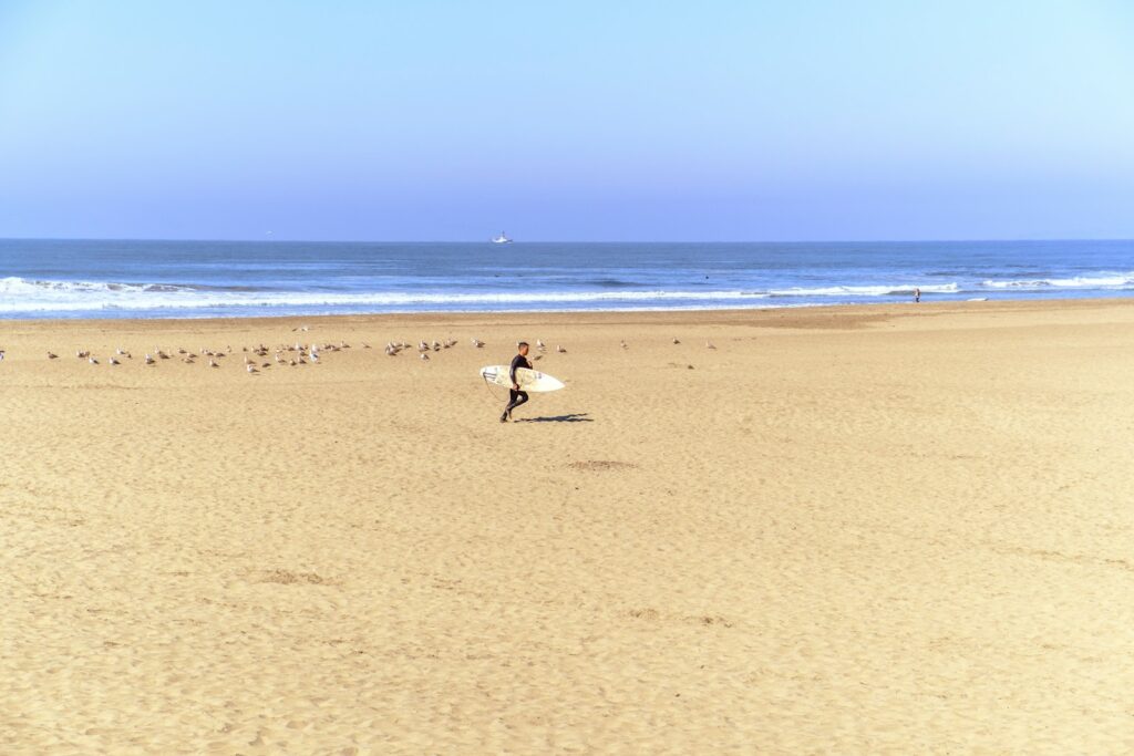 Surfer walks on a beach towards the ocean.
