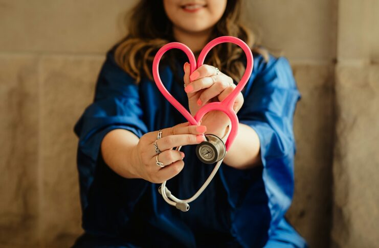 A woman holding a stethoscope in the shape of a love heart.