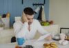 Rising Financial Strain Linked to Worsening Health Among Staff A man sitting at a table looking worried while looking at a bill.