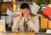 Workplace Stress Linked to Rising Mistakes Among UK Workers A stressed office worker overwhelmed by paperwork in office environment, demonstrating burnout.