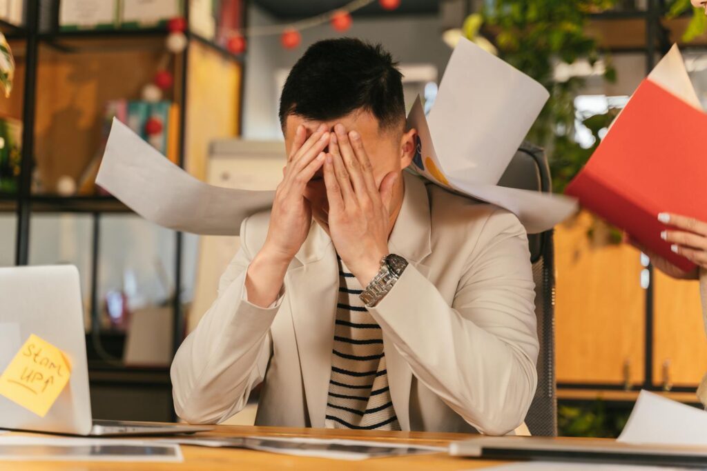 A stressed office worker overwhelmed by paperwork in office environment, demonstrating burnout.