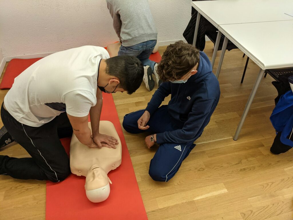Two people do first aid training on a dummy.
