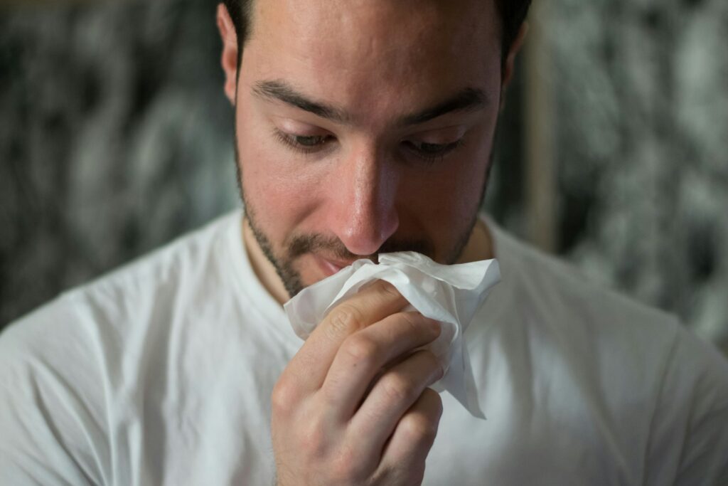 A man wipes his nose, suggesting he has a cold or flu.