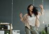 World’s Happiest Workplaces Named as Wellbeing and Trust Drive Success A woman joyfully dancing in an office with arms raised.