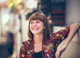 Midlife Health Support Linked To Women’s Retention At Work woman in floral-themed cardigan leaning on fence in bokeh photography